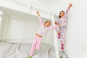 Kinder im weichen warmen Pyjama spielen im Bett foto