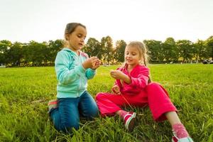 Zwei kleine Mädchen blasen Seifenblasen, Outdoor-Shooting foto