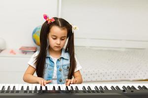 süßes kleines mädchen spielt auf klavier, synthesizer. Ausbildung. Bildung. Schule. Ästhetische Ausbildung. Grundschulklassen. foto