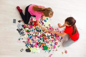 Kinder spielen mit einem Spielzeugdesigner auf dem Boden des Kinderzimmers. Zwei Kinder spielen mit bunten Blöcken. Kindergarten Lernspiele. Nahaufnahme. foto