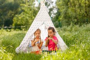 Zwei kleine Mädchen spielen in einem Zelt im Park foto