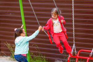 kleines Kind auf Schaukel auf dem Spielplatz im Freien foto