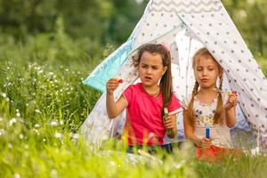 kindheits- und hyggekonzept - glückliche kleine mädchen, die im kinderzelt spielen foto