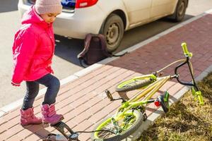 Ein kleines Mädchen pumpt einen Fahrradreifen auf. foto