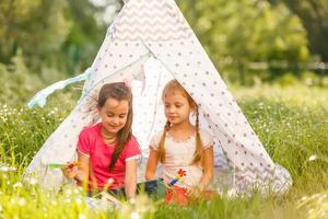 Zwei kleine Mädchen spielen in der Nähe des Wigwam-Zeltes foto