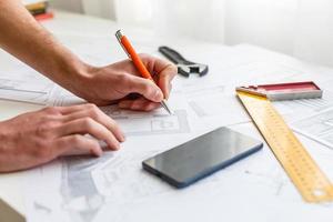 Hochwinkelansicht des Tablet-PC mit Blaupause und Modellstruktur auf dem Tisch foto