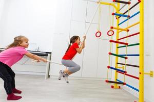 Kleine Kinder klettern in der Turnhalle der Schule an der Sprossenwand foto