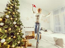 Eine als Weihnachtsmann verkleidete Frau schmückt einen Weihnachtsbaum foto