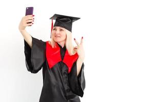 Aufgeregte, glückliche Studentin steht im Mantel, lächelt und schaut in die Kamera foto