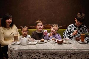 glückliche familie, die zusammen desserts im gemütlichen café isst und spaß hat. foto