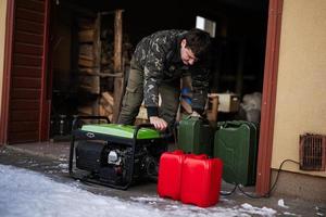 Mann trägt Militärjacke mit tragbarem mobilem Backup-Standby-Benzingenerator. foto