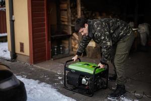 Mann trägt Militärjacke mit tragbarem mobilem Backup-Standby-Benzingenerator. foto