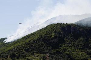 Feuerwehrhubschrauber lässt Wasser auf Waldbrände am Berg in Sant'Antonio Abate, Kampanien, Italien fallen. foto