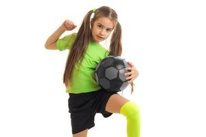 süßes kleines Mädchen in grüner Uniform, das mit Fußball spielt foto