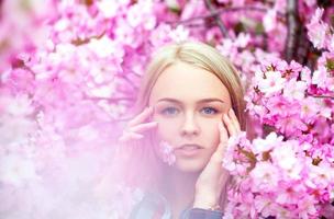 coole junge Blondine mit rosa Blume im Mund foto