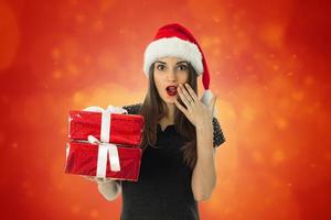 süßes Mädchen in Weihnachtsmütze mit roter Geschenkbox foto