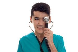 glücklicher junger brünetter Mann Arzt in blauer Uniform mit Stethoskop lächelnd isoliert auf weißem Hintergrund foto