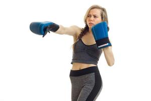 Schönes junges Mädchen mit einer Sense in einem grauen Sportanzug machen in Boxhandschuhen foto