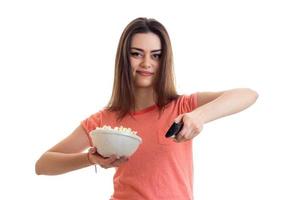 hübsche brünette frau, die einen fernseher mit popcorn anschaut foto