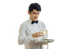 Horizontales Porträt eines attraktiven, lächelnden Kellners, der ein Tablett mit Weingläsern trägt foto