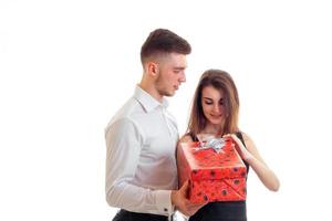 Ein junges Mädchen steht neben einem charmanten Mann und öffnet ein Geschenk foto