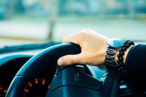 männliche hand mit armband und uhr beim autofahren foto