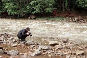 Der Fotograf fotografiert den rauen Fluss foto