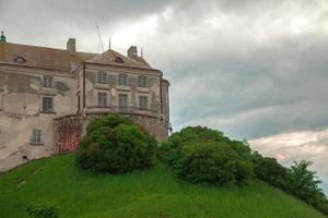 Altes Schloss steht auf einem grünen Hügel foto