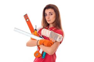 Junge charmante Baumeisterin in Uniform mit vielen Werkzeugen macht die Renovierung isoliert auf weißem Hintergrund foto