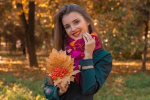 schönes glückliches Mädchen, das Herbstblätter in der Nähe hält foto