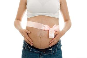 Schwangere Frau posiert mit rosa Klebeband auf ihrem Bauch isoliert auf weißem Hintergrund foto