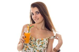 verführerische junge dame mit orangefarbenem cocktail in den händen zieht sich aus und schaut isoliert auf weißem hintergrund in die kamera foto