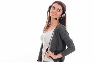 Hübsche junge Geschäftsfrau, die im Callcenter mit Kopfhörern und Mikrofon arbeitet und wegschaut und isoliert auf weißem Hintergrund lächelt foto