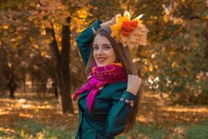 Lächelndes Mädchen steht im Park und hob die Hände mit Blättern Rowan foto
