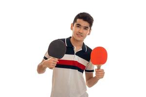 Der junge Mann steht gerade und hält Schläger für Tischtennis auf einem weißen Hintergrund foto