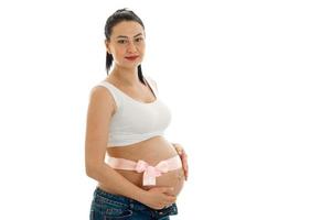 Eine junge schwangere Frau steht seitlich mit einem Band auf dem Bauch isoliert auf weißem Hintergrund foto