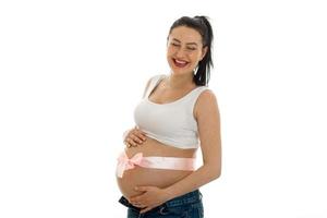 glückliches schwangeres brünettes Mädchen in dickem Bauch posiert isoliert auf weißem Hintergrund foto