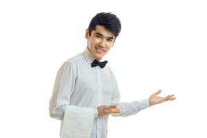 Der junge, attraktive Kellner hält ein Handtuch bereit und lächelt foto