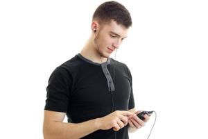 charmanter junger Mann im schwarzen Hemd sieht in Handy-Nahaufnahme aus foto