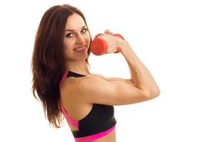 Nahaufnahmeporträt einer jungen starken Sportbrünette mit Dumbells oben in der Hand foto