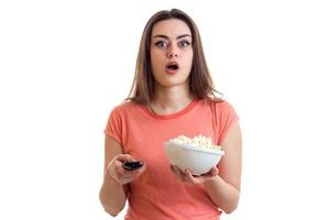 überraschtes junges Mädchen, das mit Popcorn fernsieht foto