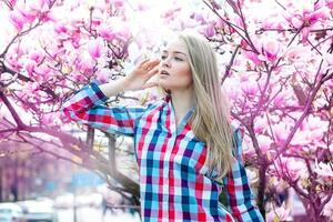 träumende junge blonde frau, die mit blumen wegschaut foto