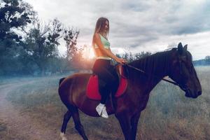charmante Dame mit Massagedüsen in Sportbekleidung auf einem Pferd foto