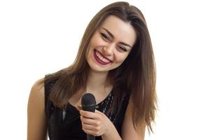 Fröhliches junges Mädchen in schwarzem Kleid, das Karaoke singt foto