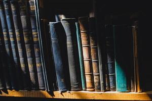 alte Bücher im Regal in der Bibliothek unter dem Sonnenstrahl foto