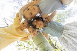 gruppe asiatischer und kaukasischer glücklicher kinder, die sich zusammenkauern, auf die kamera herabblicken und lächeln foto