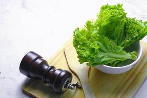 Salat in einer weißen Schüssel und einem Schneidebrett auf einem weißen Tisch. Gemüsesalat. vegetarisches Essen. sauberes Essen. grünes Gemüse. foto
