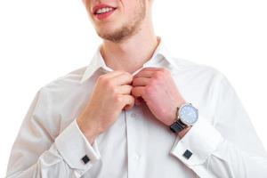 Porträt eines jungen Mannes, der lächelt und ein Hemd in der Nähe des Knopfes übergibt foto