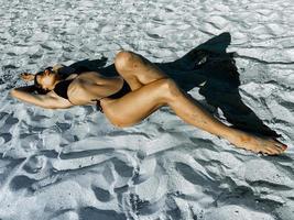 sexy junge dame, die auf weißem sand ein sonnenbad nimmt foto