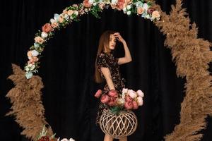 schöne Frau posiert im Kreis aus Totholz im Kleid mit Blumendruck foto